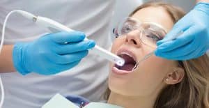 Patient receiving dental examination with intraoral camera, highlighting dental health and restoration monitoring.