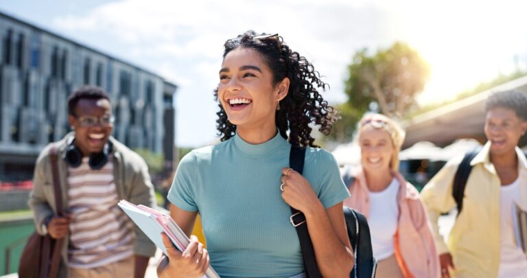 Group of young adults smiling and walking together outdoors, showcasing camaraderie and a lively atmosphere, relevant to discussions on dental health and lifestyle choices.