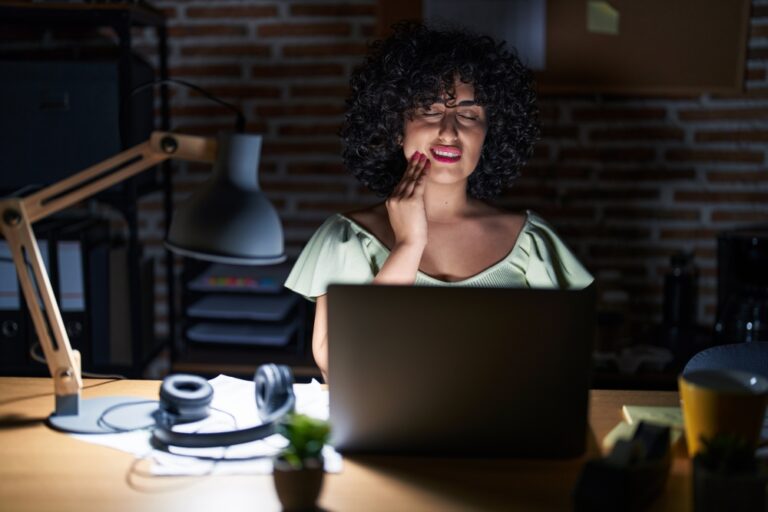 woman working at laptop at night with toothache