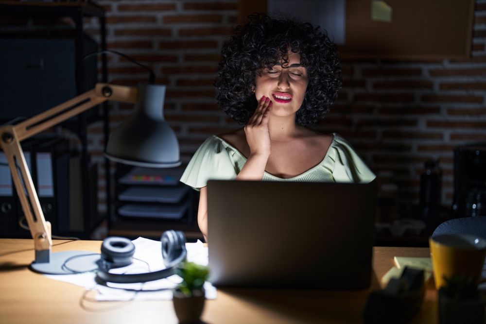 woman working at laptop at night with toothache