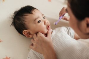 mother brushing baby's teeth