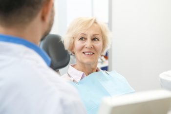 Patient smiling during dental consultation with a dentist, emphasizing personalized care and veneer maintenance at Lexington Dental of Owasso.